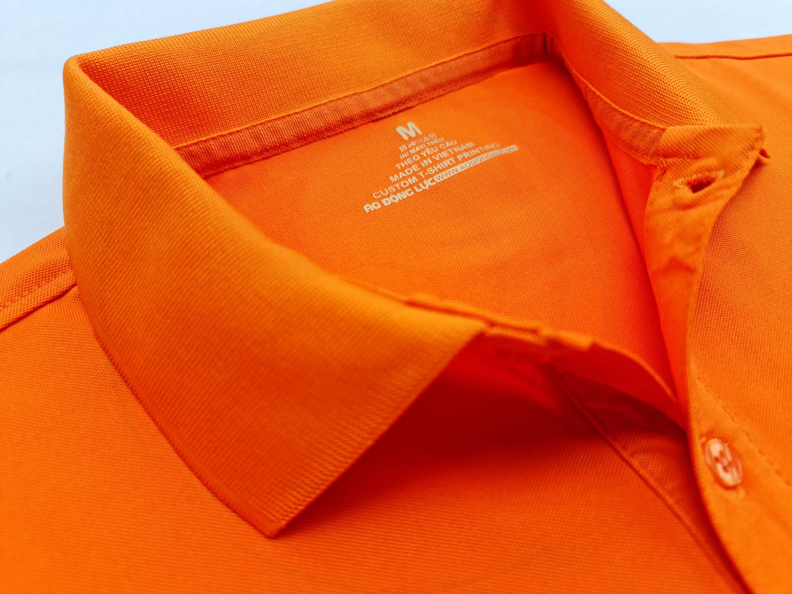 Chi tiết cổ áo áo thun cổ trụ polo bo trơn cá sấu lạnh poly thấm hút màu cam