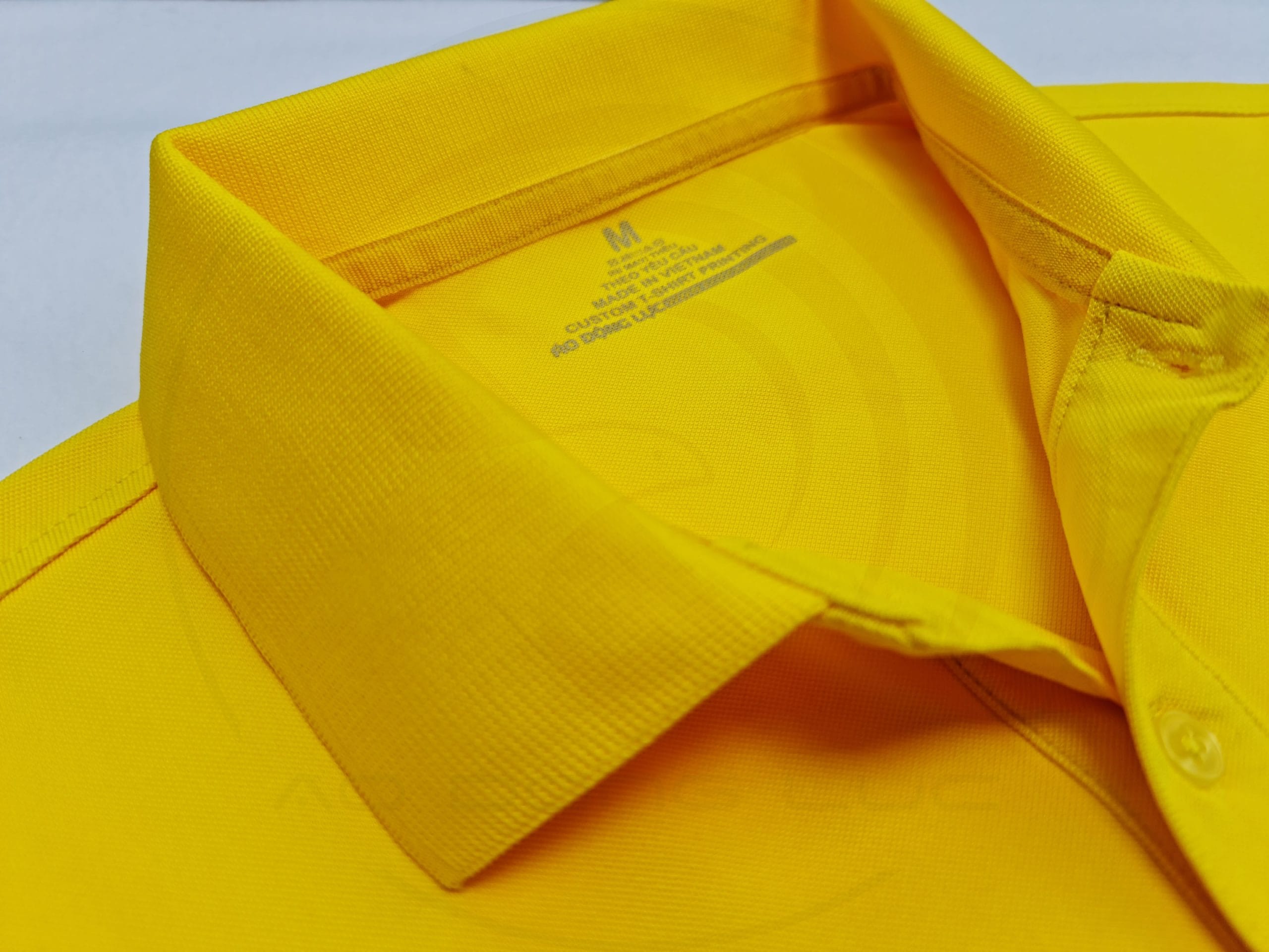 Chi tiết cổ áo áo thun cổ trụ polo bo trơn cá sấu lạnh poly thấm hút màu vàng nghệ