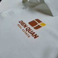 Hình in chuyển nhiệt logo lên áo thun đồng phục polo bo trơn màu trắng