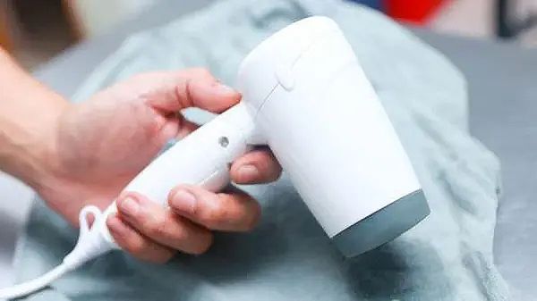Một cái máy cầm tay đang được sử dụng để giặt một mảnh vải